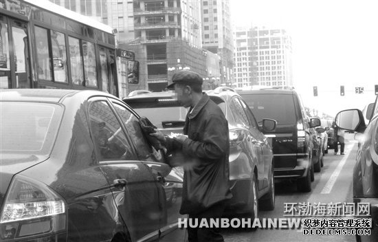 在建設(shè)路新華道路口“擦車(chē)”的行乞者。田菲菲攝