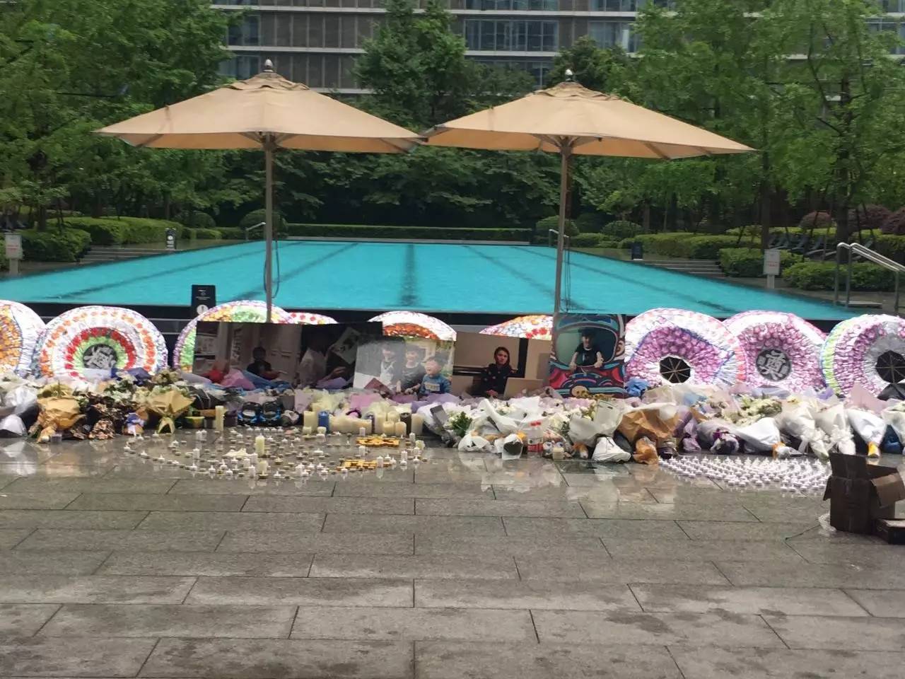 火災(zāi)后，小區(qū)業(yè)主自發(fā)組織悼唁活動，草坪上逝者照片前擺滿了花圈、花束、蠟燭。（新京報(bào)記者王婧祎攝）